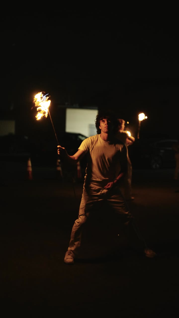 Rope dart spinner mid-throw with the lit head arcing overhead